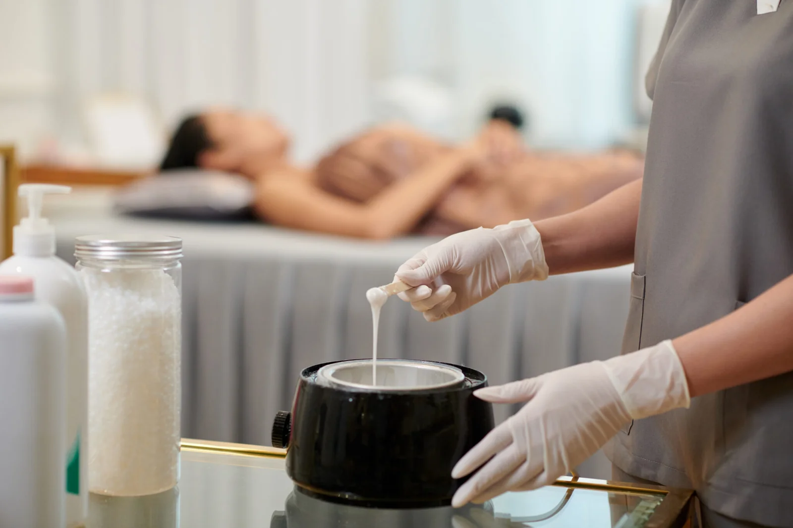esthetician melting hard wax at Skin Statements with client relaxing in background
